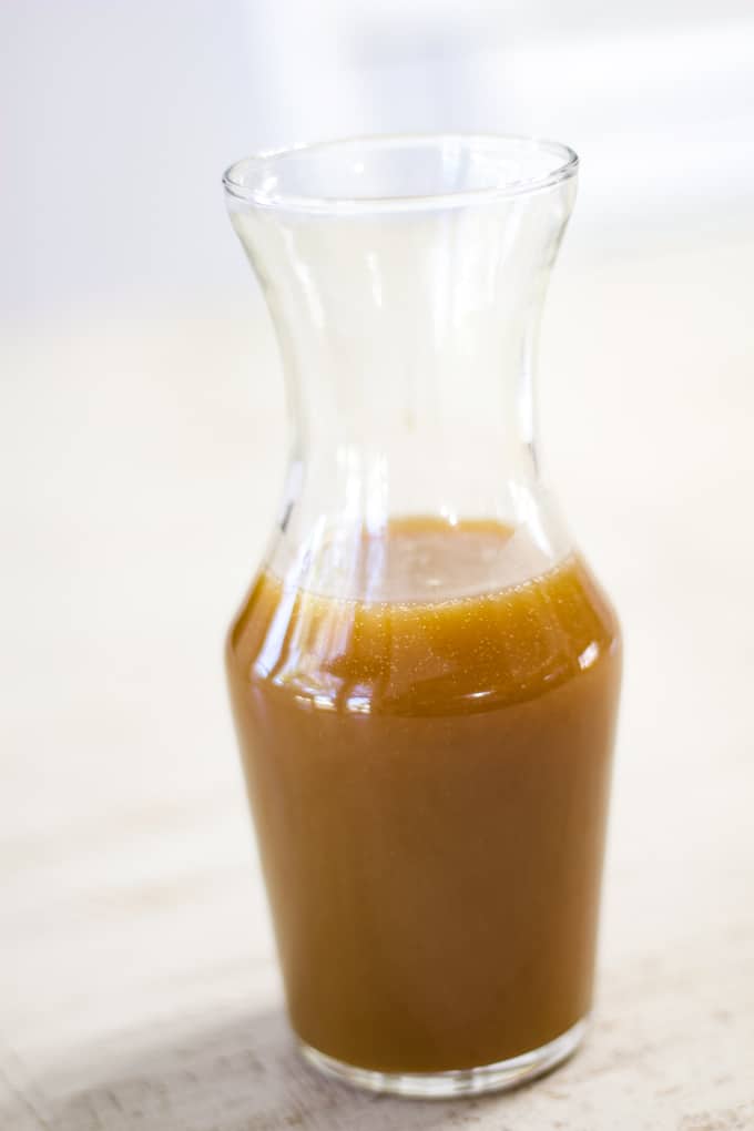Vertical shot of a clear glass bottle filled with caramel sauce.