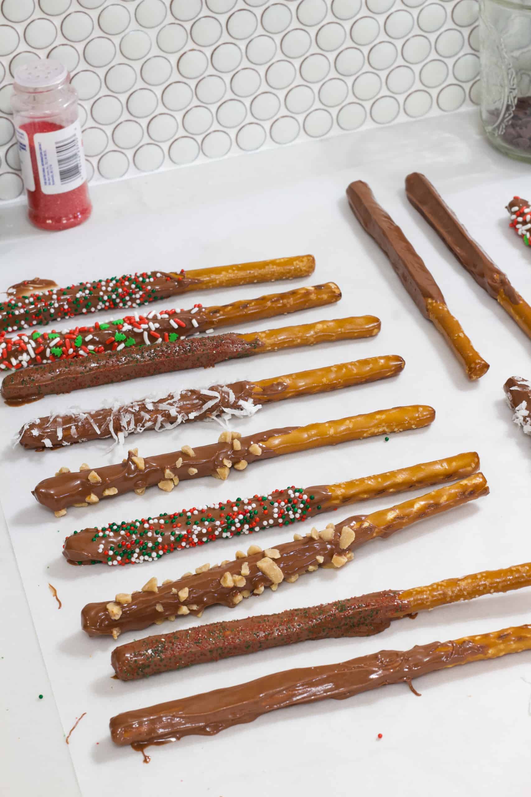 Many pretzel rods that have been dipped in milk chocolate and sprinkles added drying.