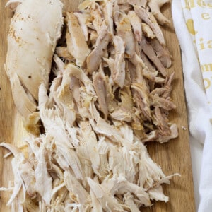 Shredded rotisserie style chicken on a wooden cutting board.