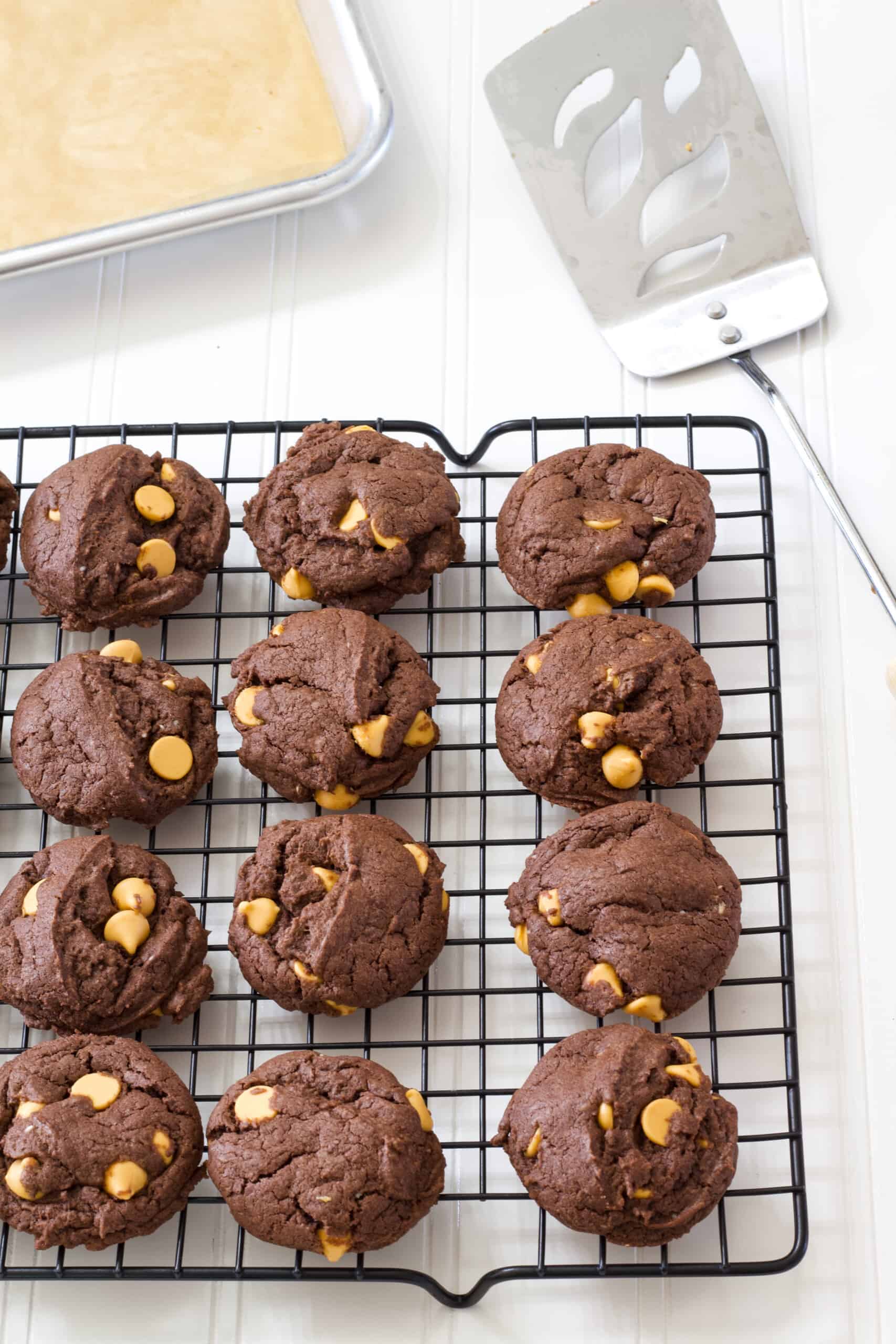 Cookies on a wire rack with a metal spatula and rimmed backing dish in the background.