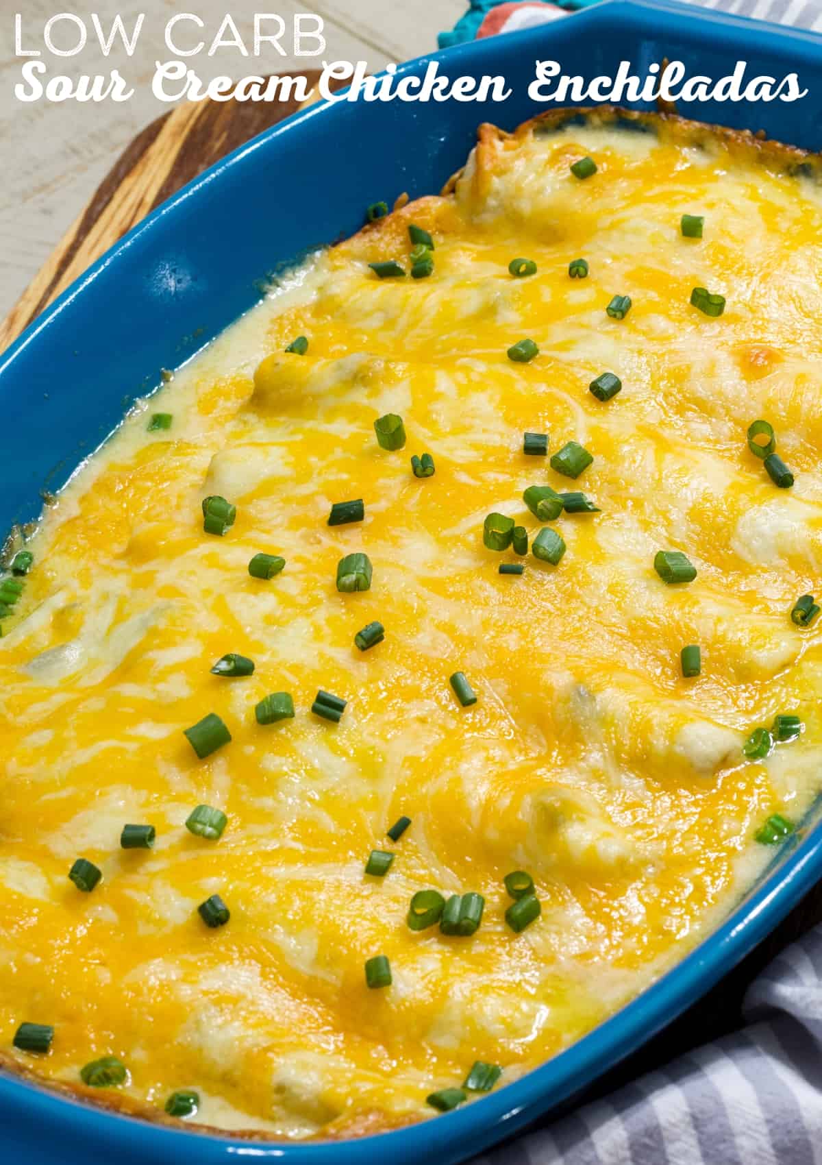 A blue casserole dish filled with sour cream chicken enchiladas topped with green onions.
