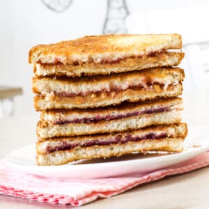 Four peanut butter and jelly sandwich halves stacked on top of each other.