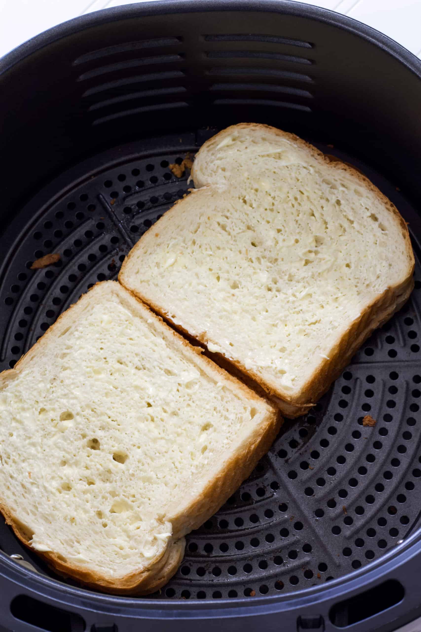 Two whole pb & j sandwiches in the air fryer basket ready to be air fried.