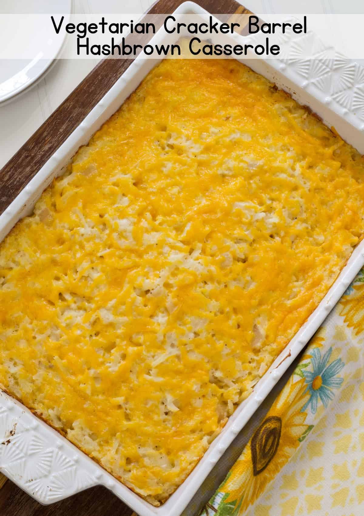 A rectangle casserole dish with the baked Vegetarian Cracker Barrel Hashbrown Casserole in it with the recipe title above it so the image can be pinned on Pinterest.