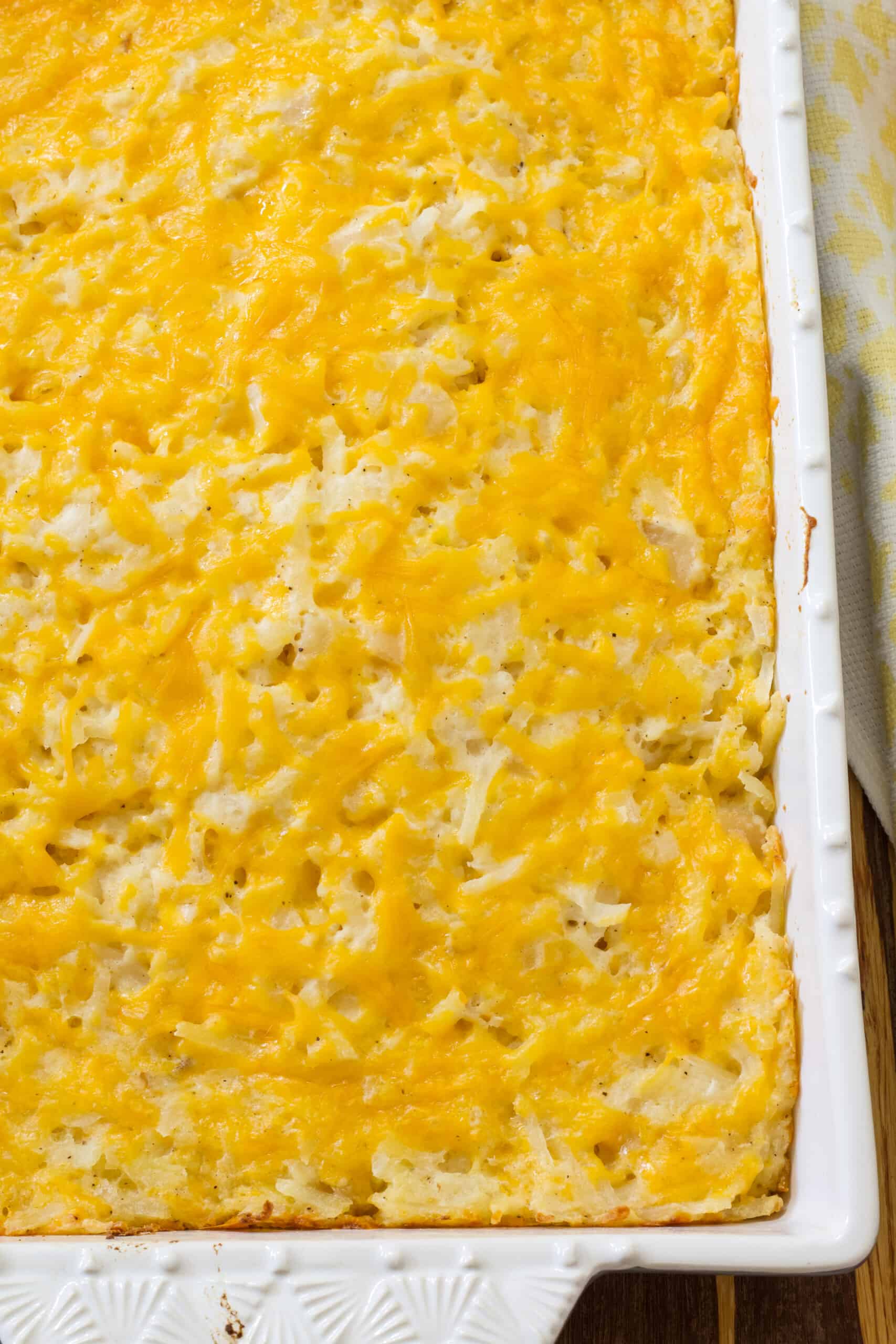 Overhead view of a portion of the cooked vegetarian cracker barrel hashbrown casserole in a rectangle baking dish.