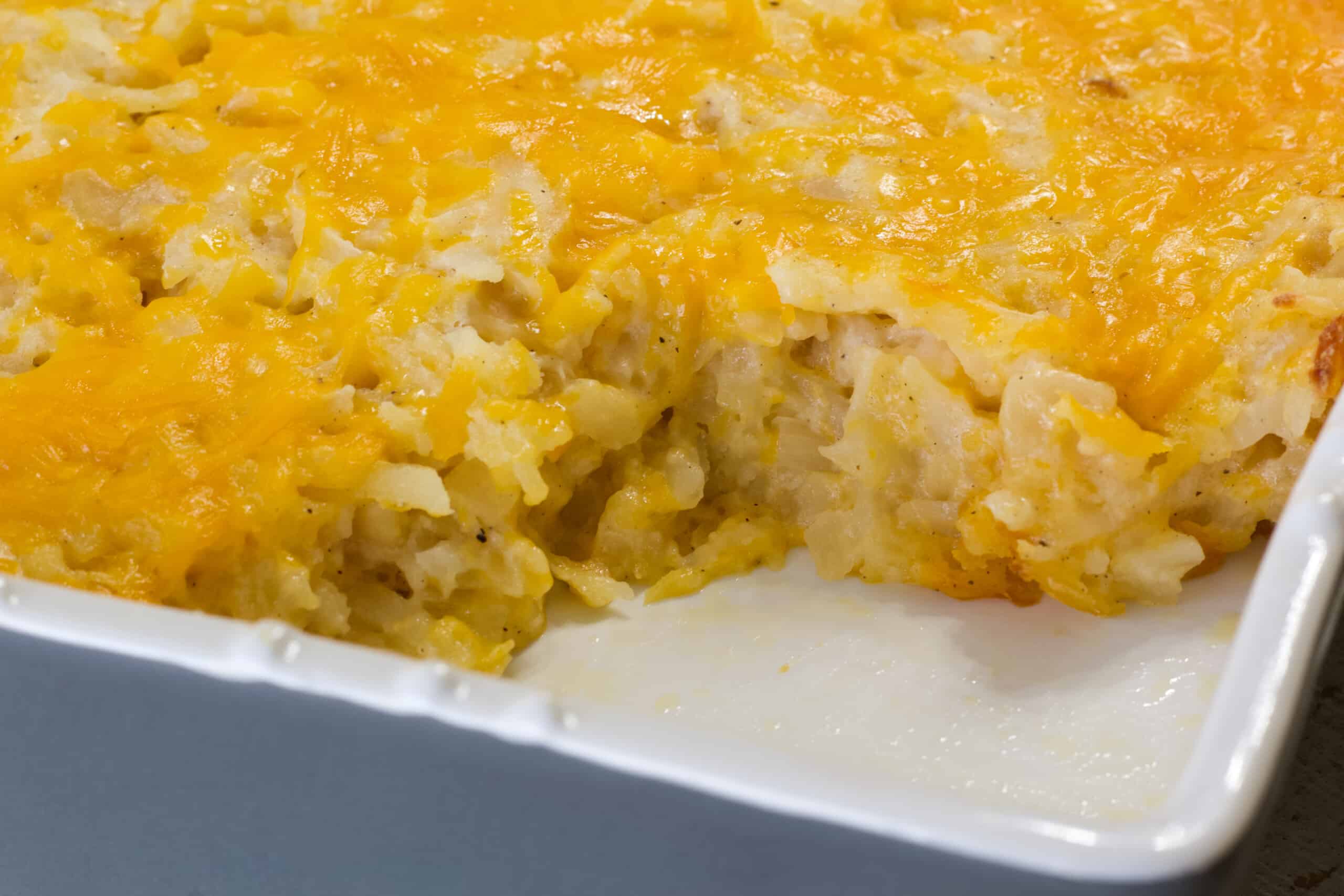 The corner of the casserole dish with one serving of the vegetarian cracker barrel hashbrown casserole with one serving missing.