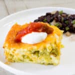 Close up side view of one serving of casserole in the foreground and blck beans in the background.