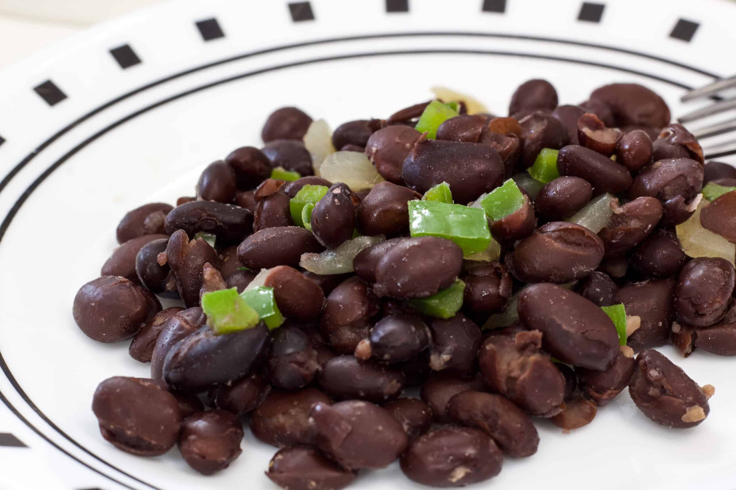 Close up of one serving of Mexican black beans on a white plate.