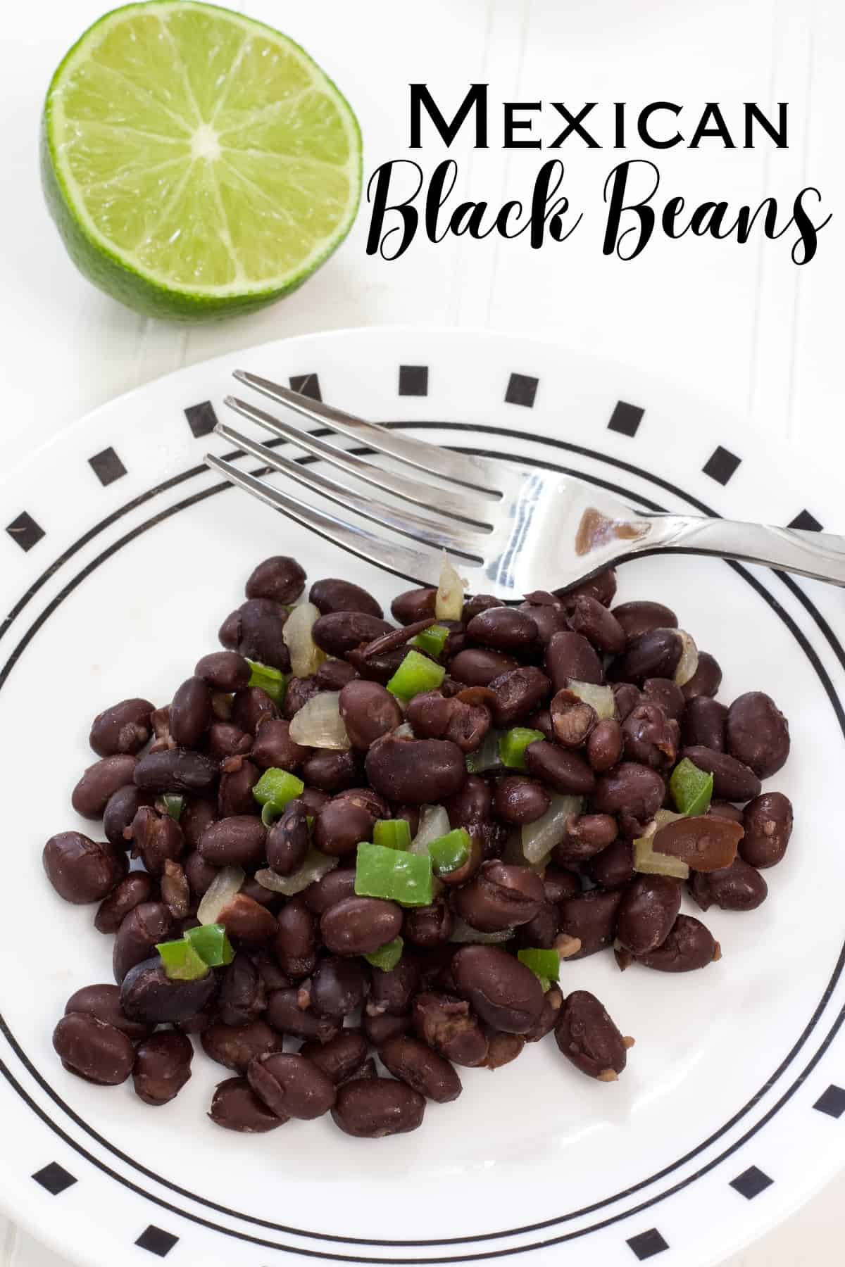 One serving of black beans on a white plate with a lime half and the title written above it so it can be pinned on Pinterest.