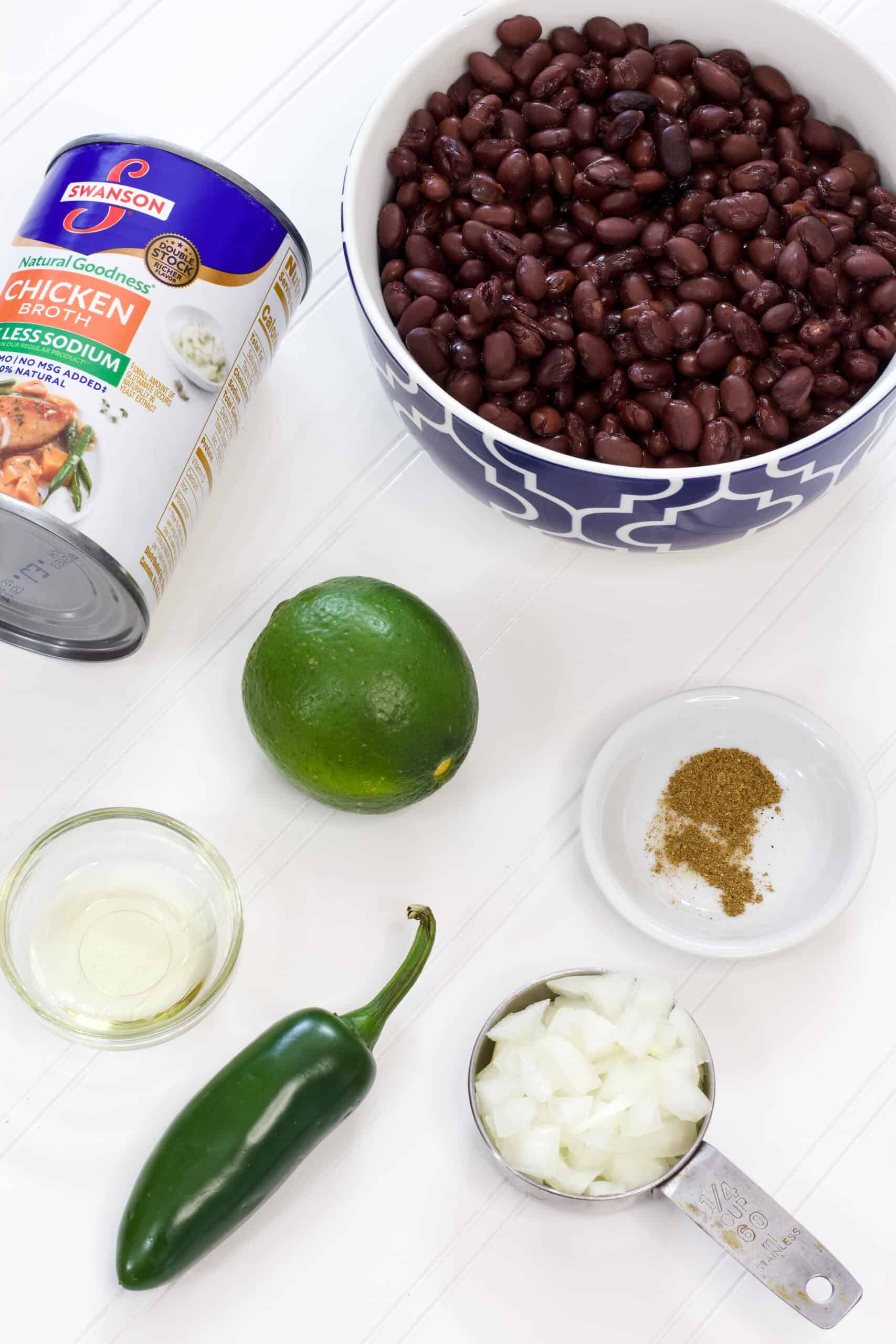 All six ingredients needed to make Easy Mexican Black Beans Recipe (with canned beans) laying on a white background.