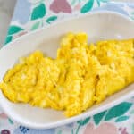 Close up shot of one serving of cheese eggs on a white plate.