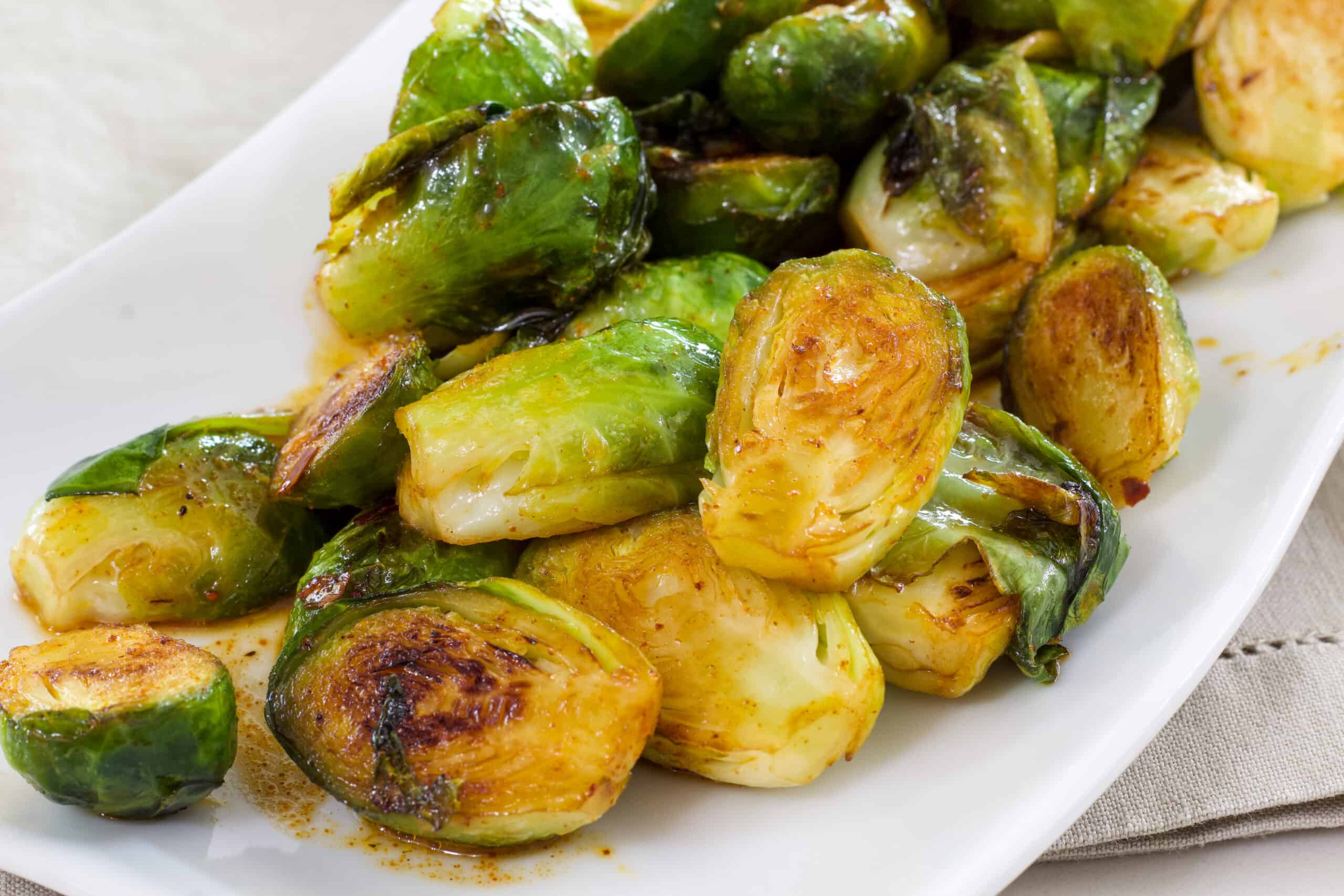 Close up of the brussels sprouts on a white serving plate.