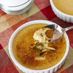 A spoonful of coffee creme brulee above the ramekin that has the remainder of the serving in it.