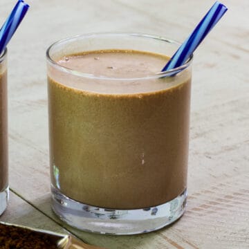 Front view of a mocha madness smoothie in a short glass with a blue striped straw sticking out of it.