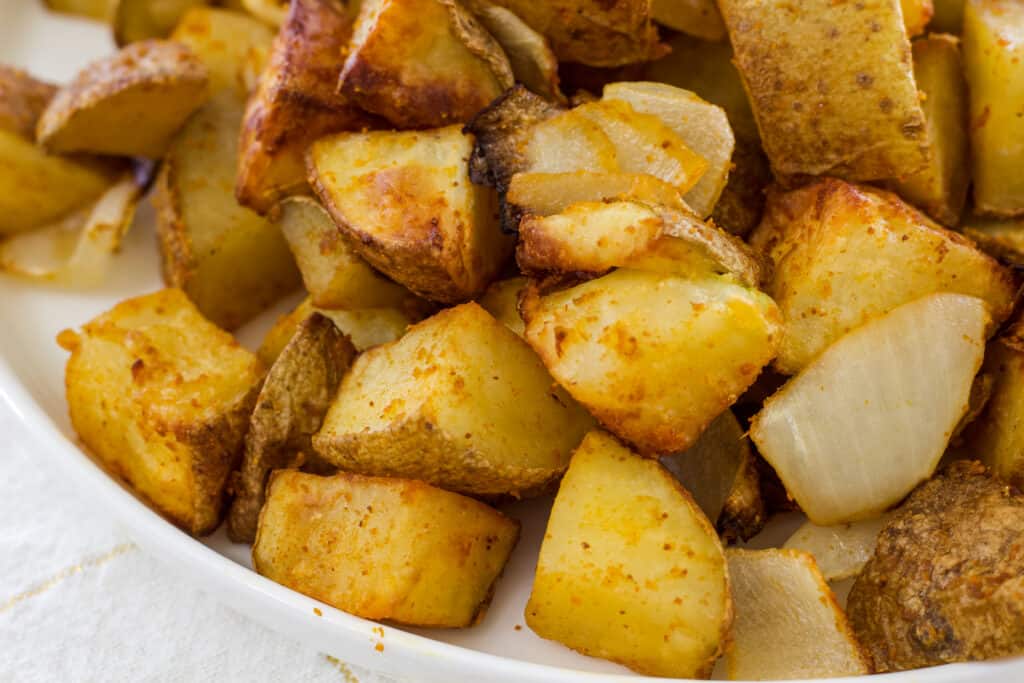 Close up shot of potatoes and onions, you can't see the entire plate, just some of it.