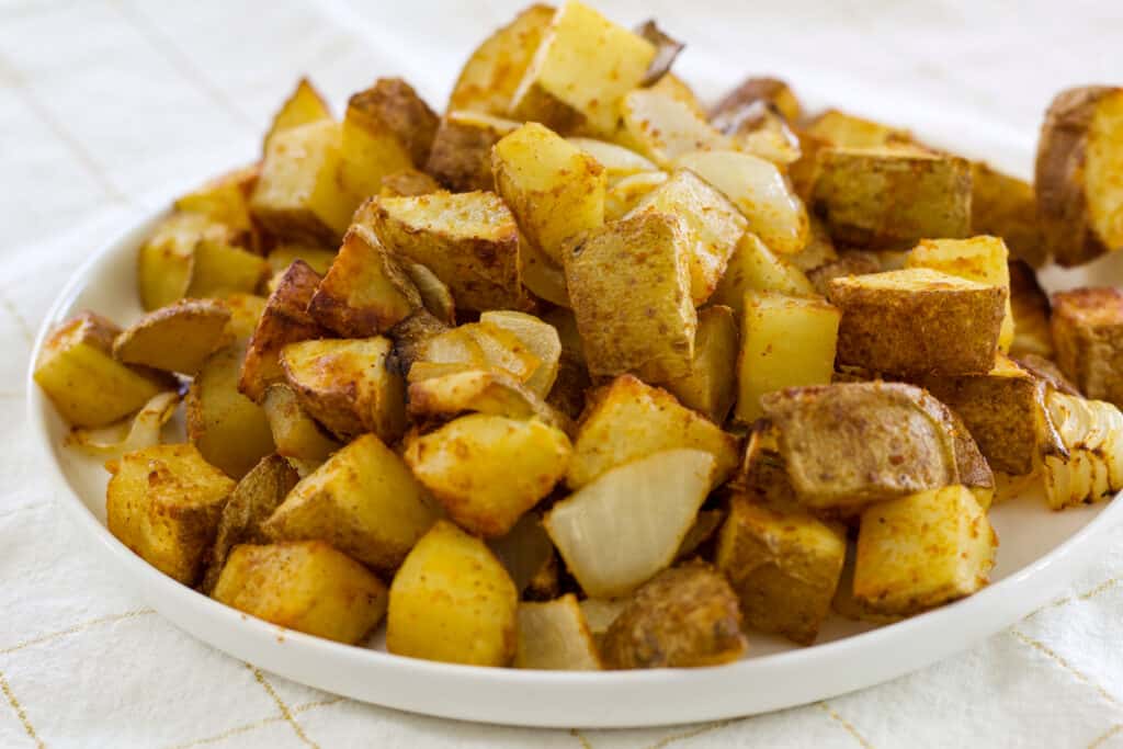 The entire plate of air fryer seasoned potatoes and onions on a white plate.