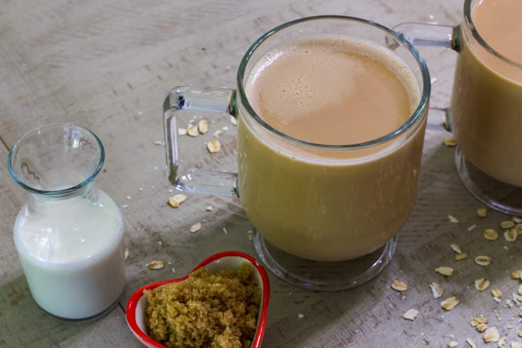 Overhead view of a cup of coffee with small containers of oat milk and brown sugar sitting next to it.