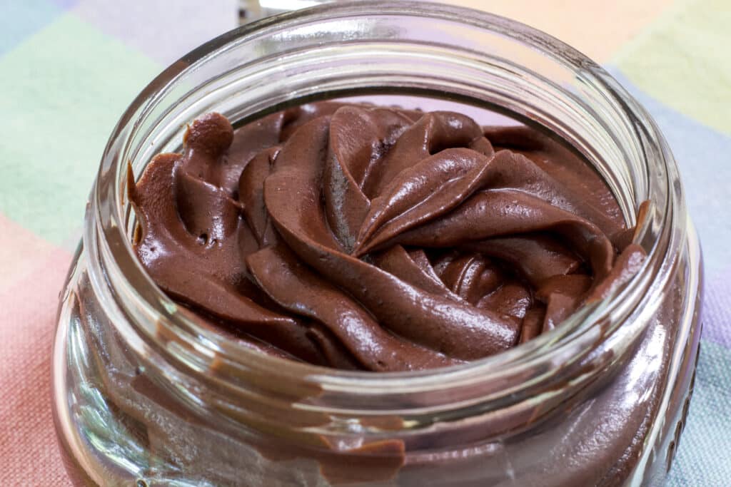 Vertical close up of the mason jar with Easy Hershey's Perfectly Chocolate Frosting Recipe in it.