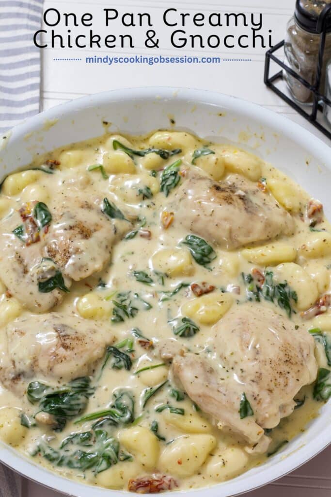 A skillet with the entire batch of easy one pan creamy chicken and gnocchi dinner recipe in it. The recipe title is at the top.