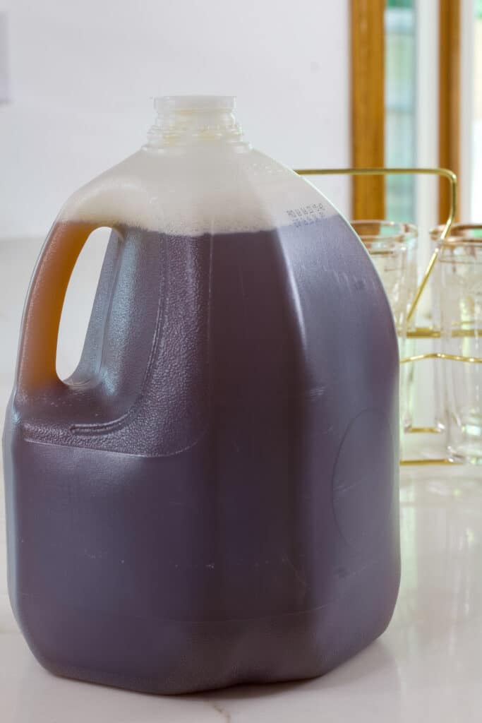 A gallon water jug full of The Best Luzianne Southern Sweet Iced Tea sitting on the counter.