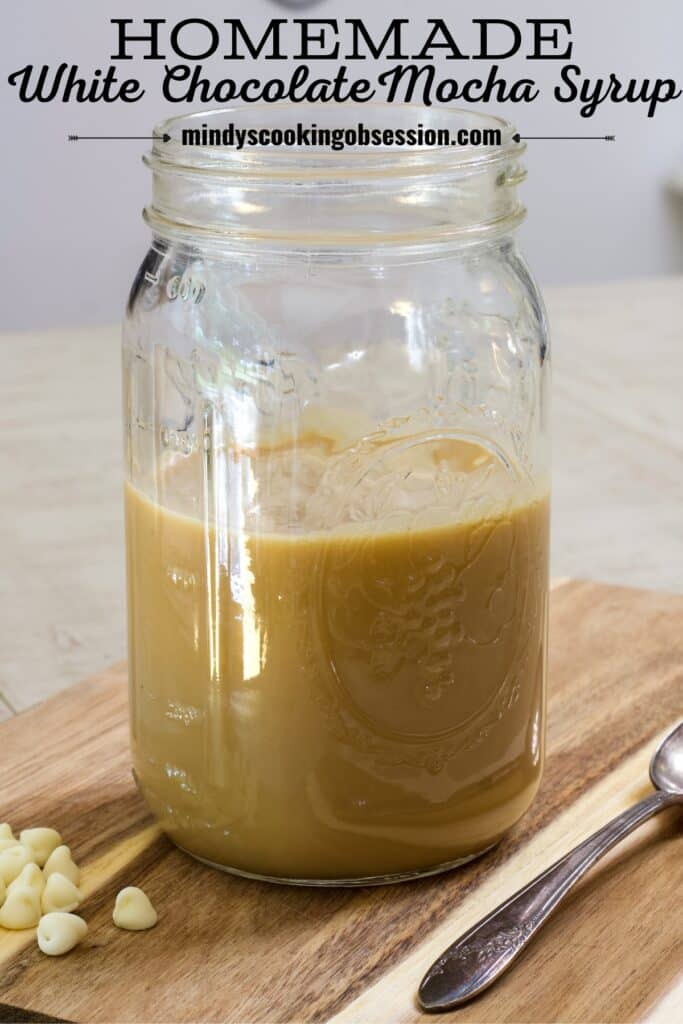 A mason jar filled with Best Homemade White Chocolate Mocha Syrup sitting on a wooden cutting board with the recipe title above it in text.