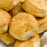 Several air fried biscuits in a cloth lined basket.