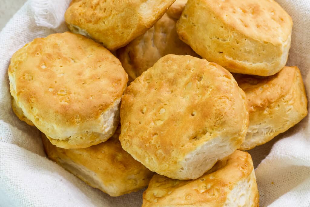 Several air fried canned pillsbury grands biscuits in a cloth lined basket.
