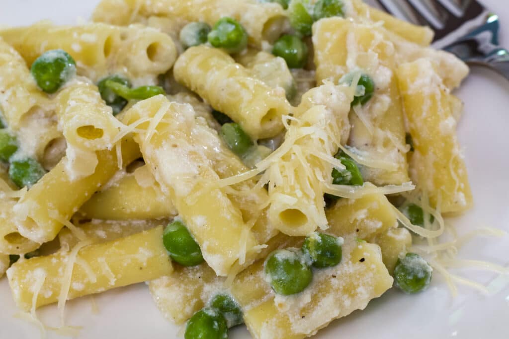 A close up of one serving of Easy Lemon Pasta with Peas and Ricotta on a white plate.