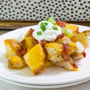 Close up of one serving of Easy Loaded Baked Potato and Chicken Casserole on a white plate.