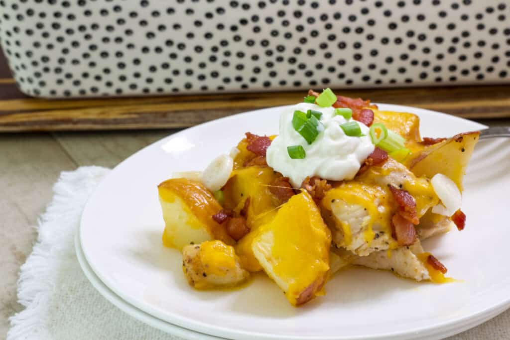A serving of Easy Loaded Baked Potato and Chicken Casserole topped with a dollop of sour cream on a white plate.