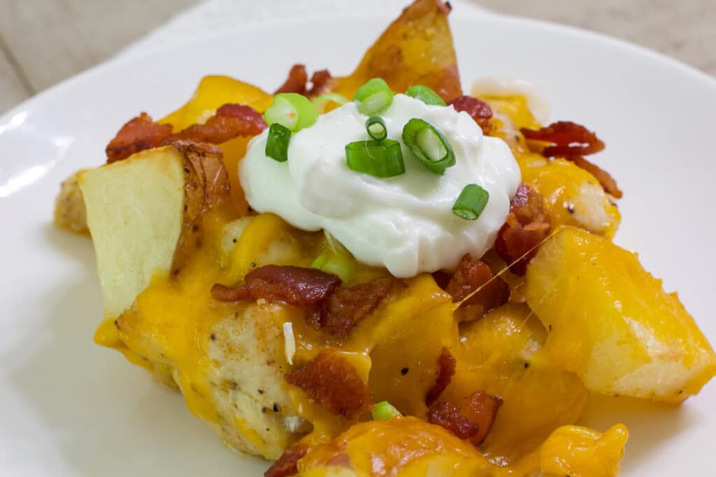 Close up of one serving of loaded chicken potato casserole topped with sour cream.
