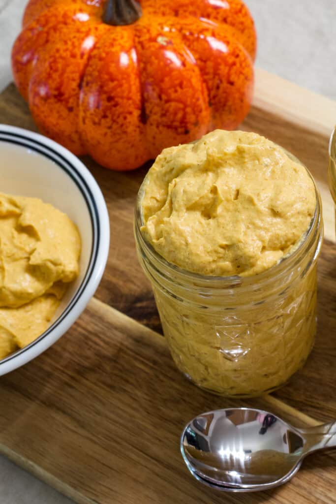 Overhead view of one small mason jar filled with pumpkin fluff and a couple of spoons sitting next to it.