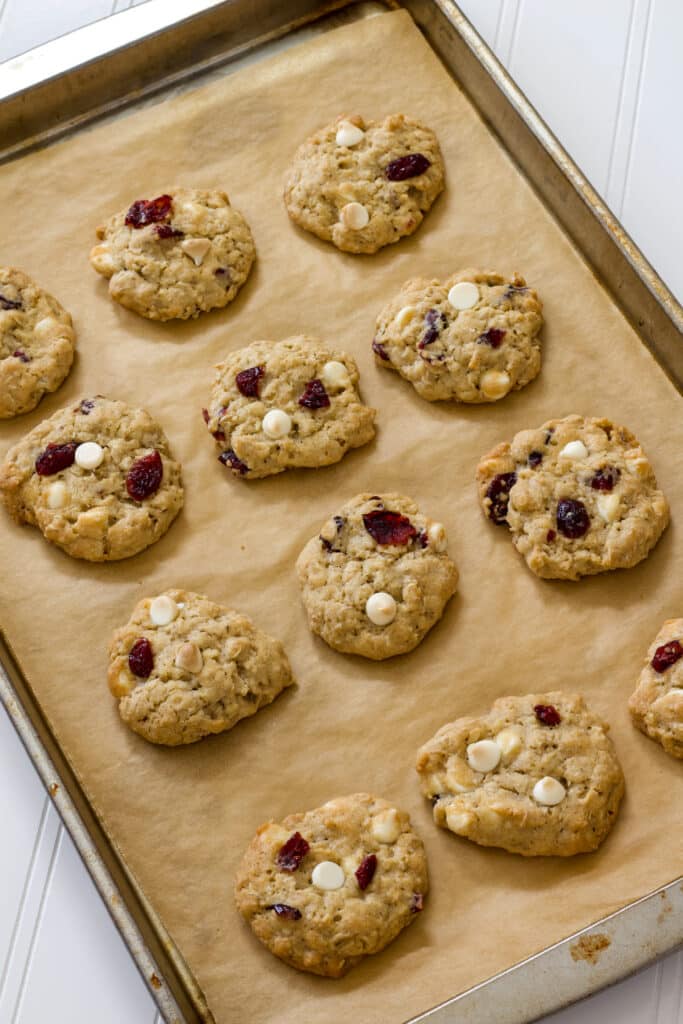 A dozen cookies on a rimmed baking sheet lined with brown parchment paper.