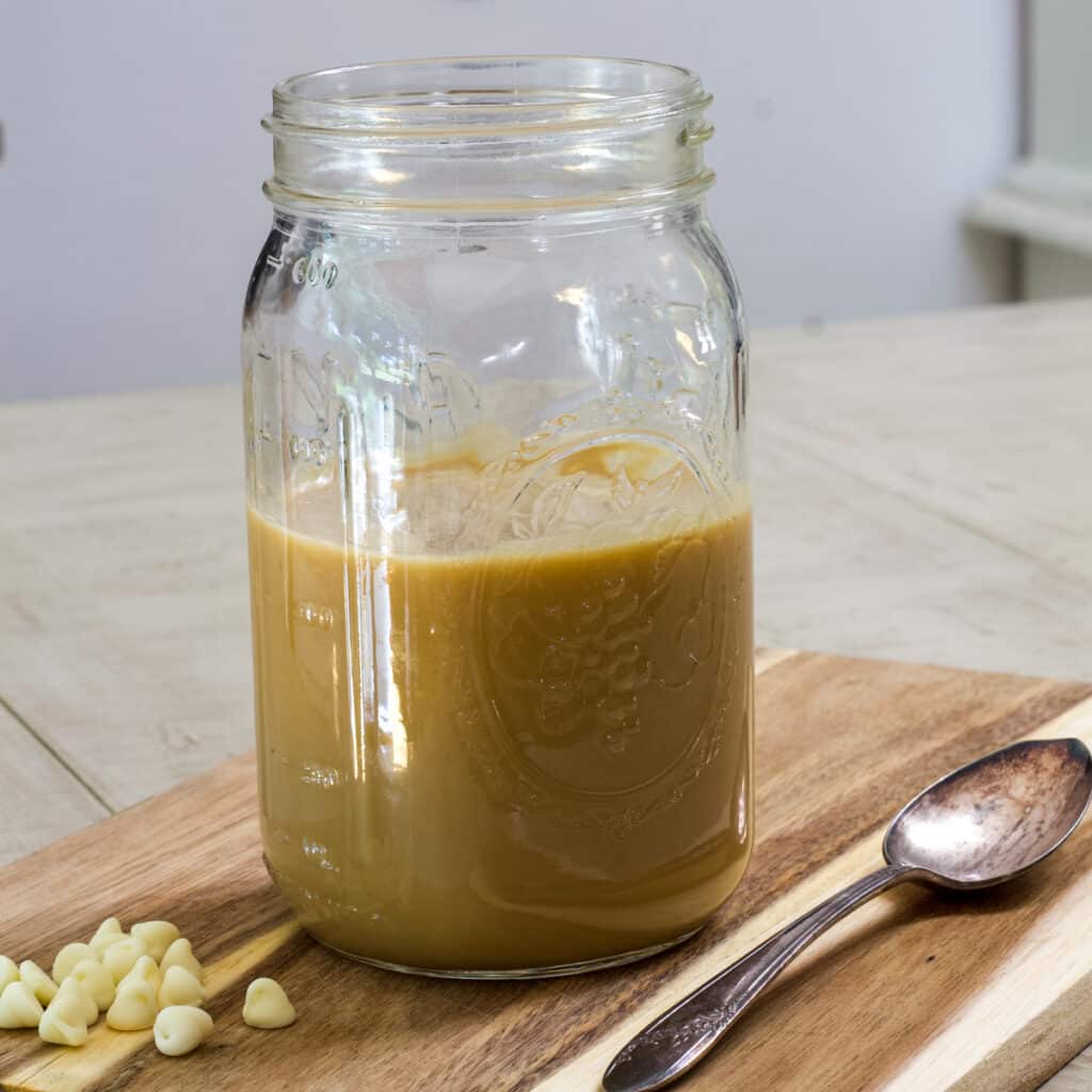 A mason jar about half full of white chocolate mocha syrup in it.