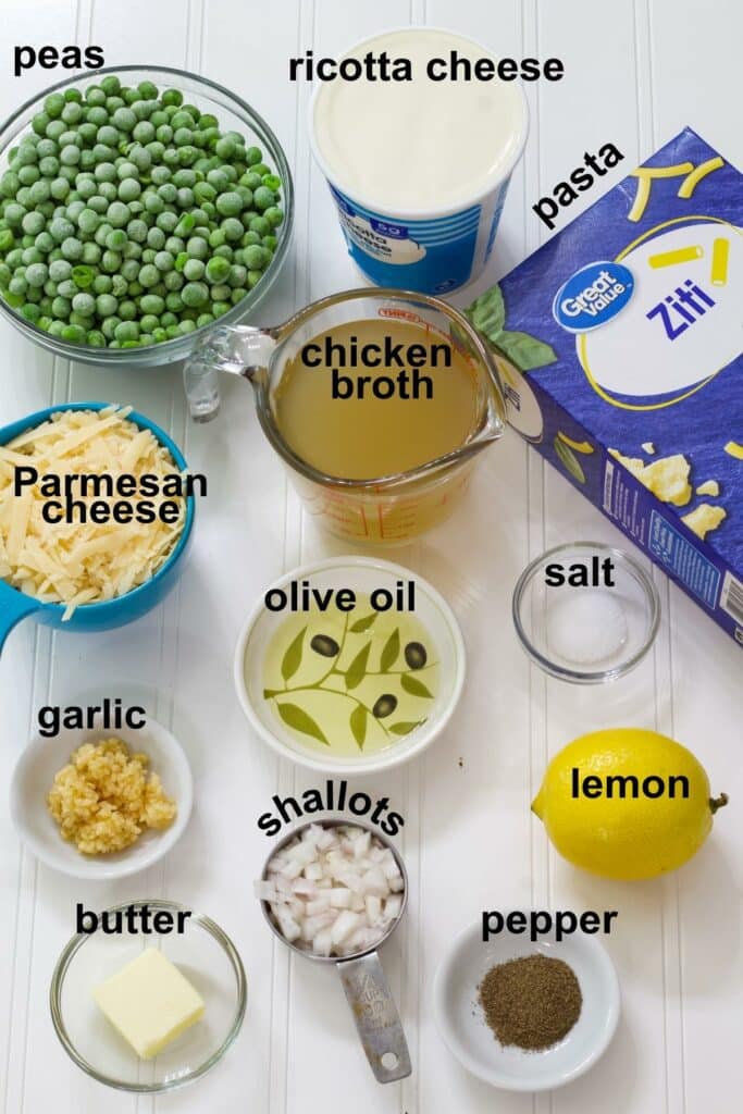 All of the ingredients needed to make lemon pasta with peas and ricotta measured and sitting on a white background.