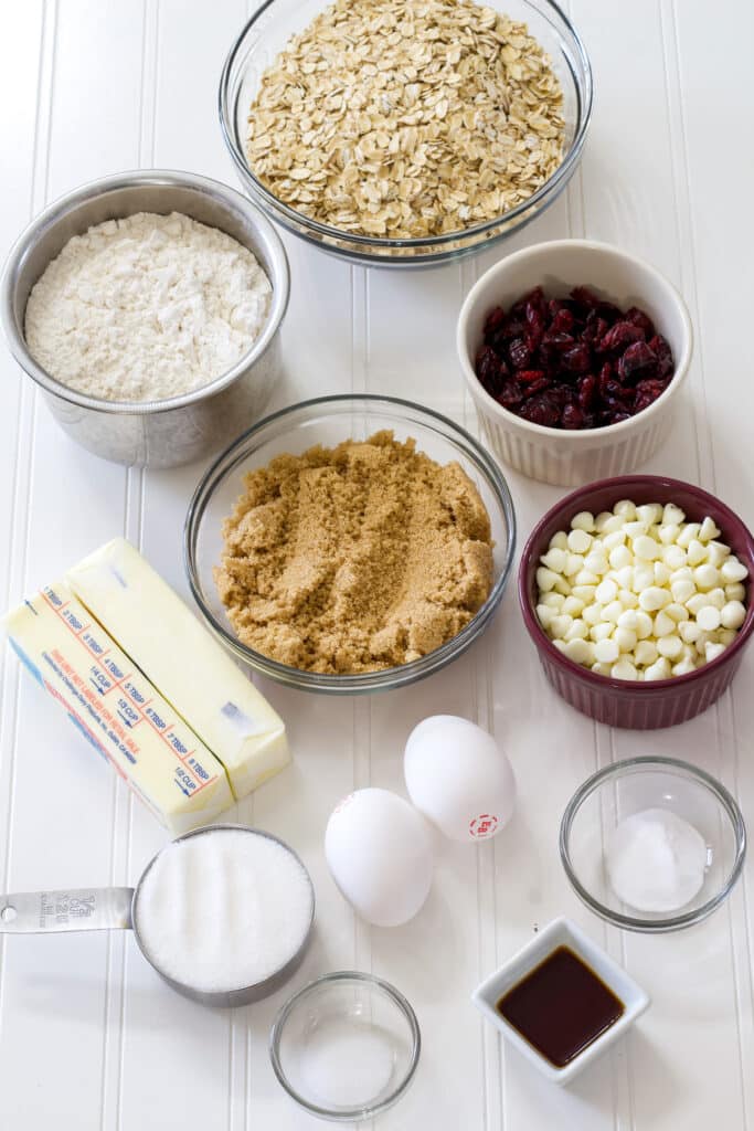 All of the ingredients to make the Soft Oatmeal White Chocolate Chip Cranberry Cookies measured out on a white table.