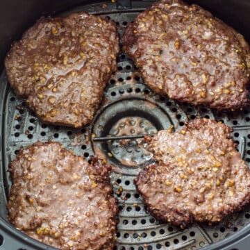 Four cooked cube steaks in the air fryer basket.
