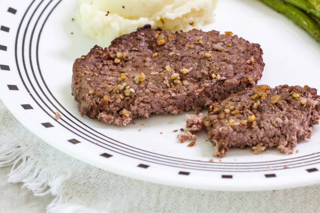 One cube steak that has a large piece cut off exposing the very slightly pink center.