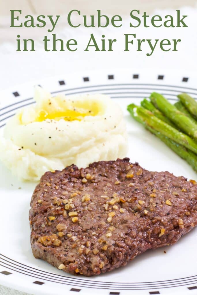 One cooked cube steak in the foreground and a serving of mashed potatoes in the background with the recipe title in text at the top.