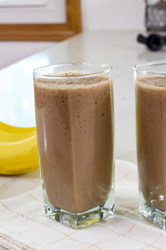 A glass full of Easy & Healthy Chocolate Coffee Smoothie sitting on a cream colored napkin.