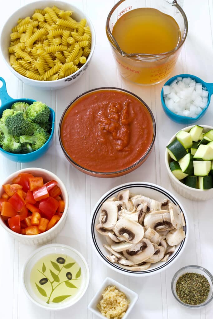 All of the ingredients needed to make vegetarian pasta chopped and measured in individual bowls.