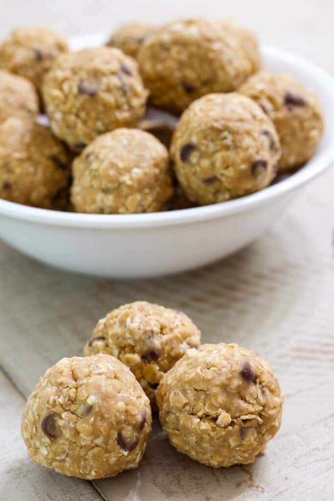 Three energy balls in the foreground and a bowl of them in the background.