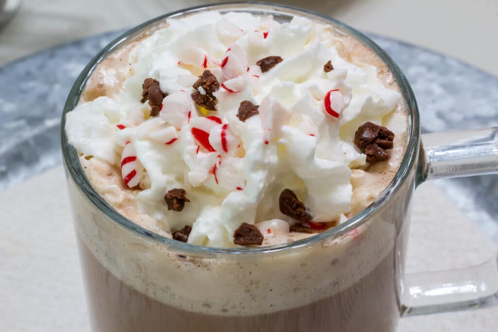 The top of one mug of peppermint mocha that is topped with whipped cream, peppermint candy pieces and chocolate chips.