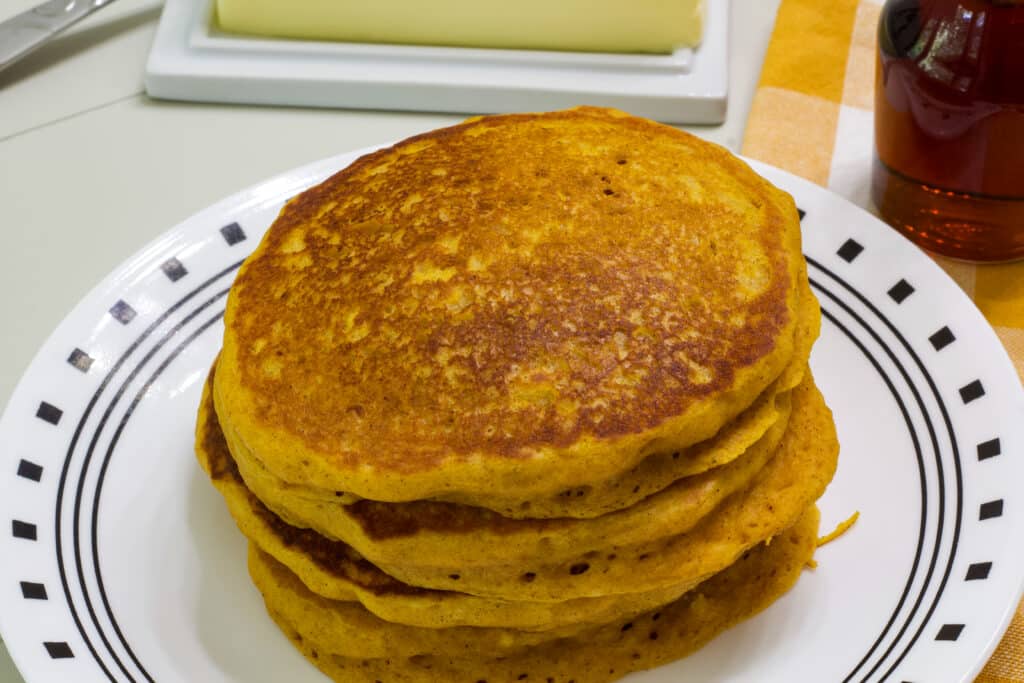 Overhead view of four pumpkin pancakes on a plate.