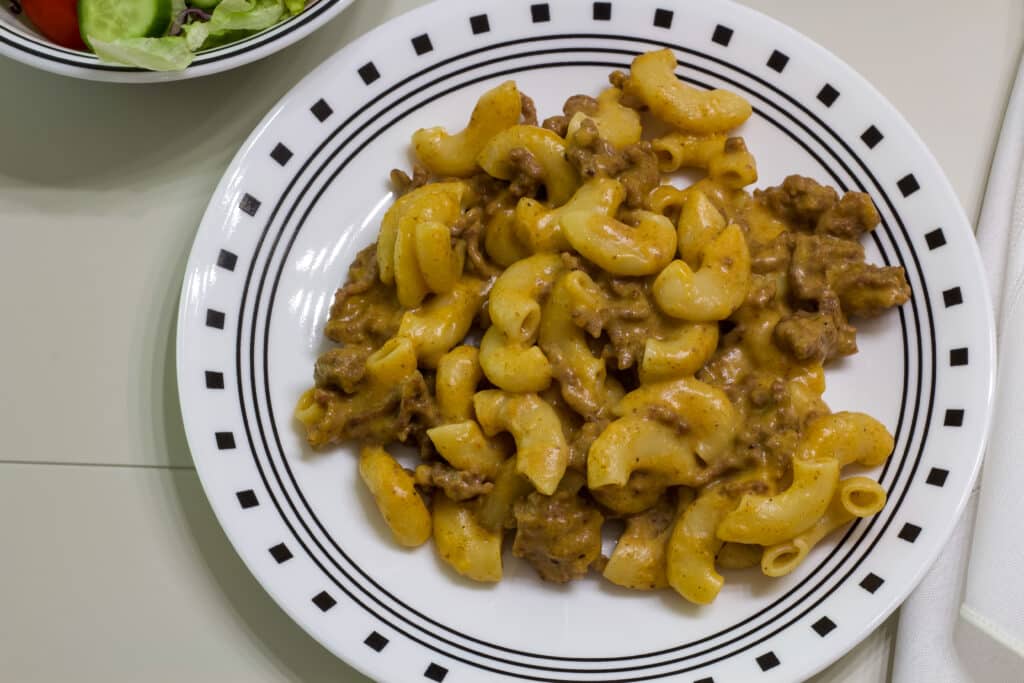 A plate with one serving of homemade hamburger helper cheeseburger macaroni on it.