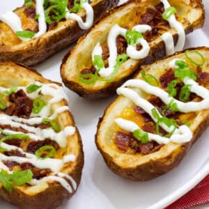 Several Homemade Loaded Potato Skins in the Air Fryer on a white plate.