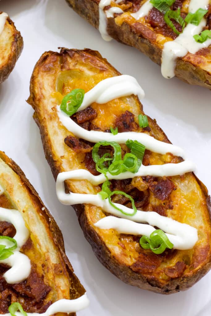 A few loaded potato skins on a plate, one is completely visible, the rest are only partially visible.