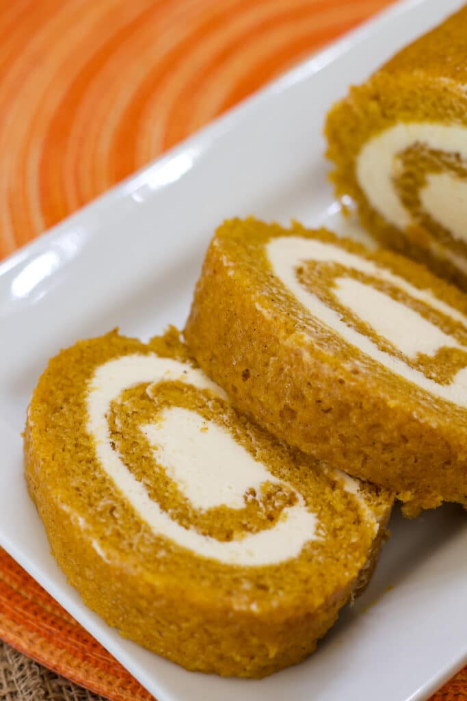 Two pieces of pumpkin roll laying down on a plate.