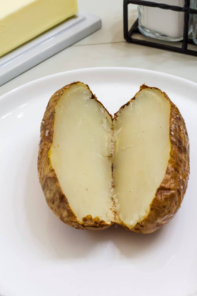 A plain baked potato cut in half lengthwise.