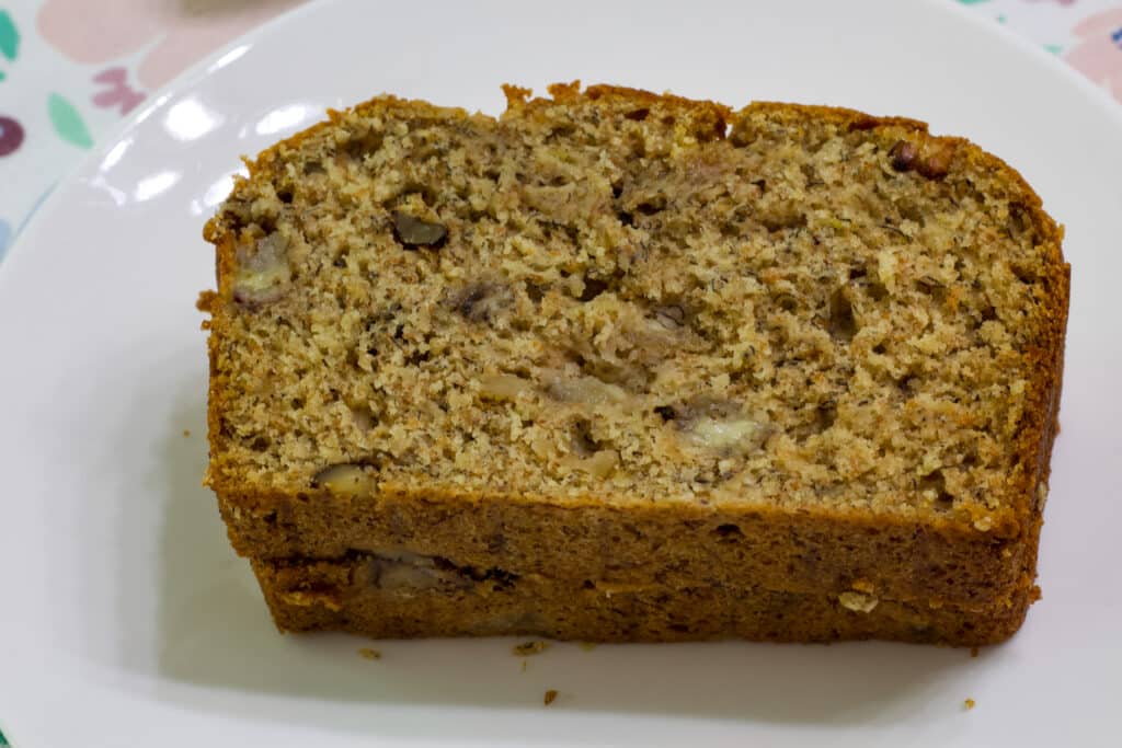 Two slices of weight watchers banana nut bread stacked on top of each other on on a white plate.